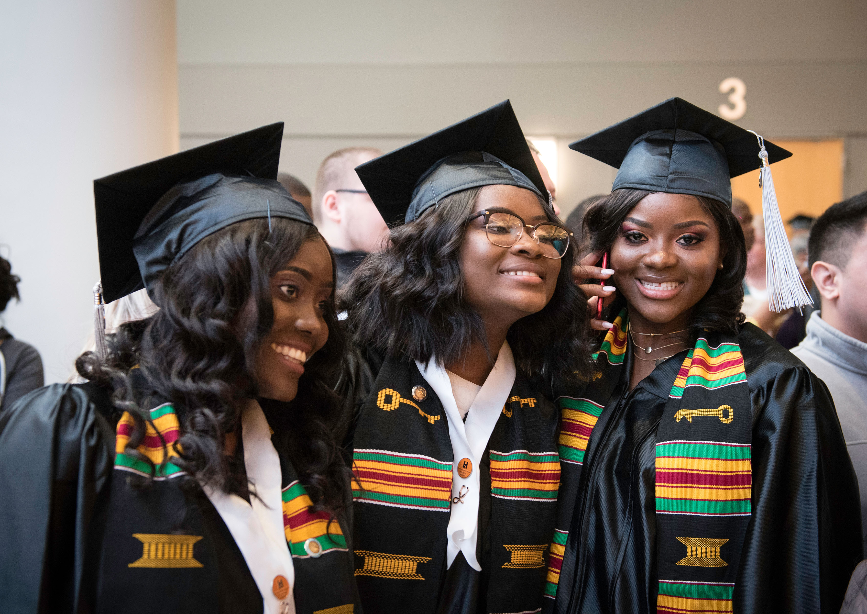 Three female black graduates in cap and gown